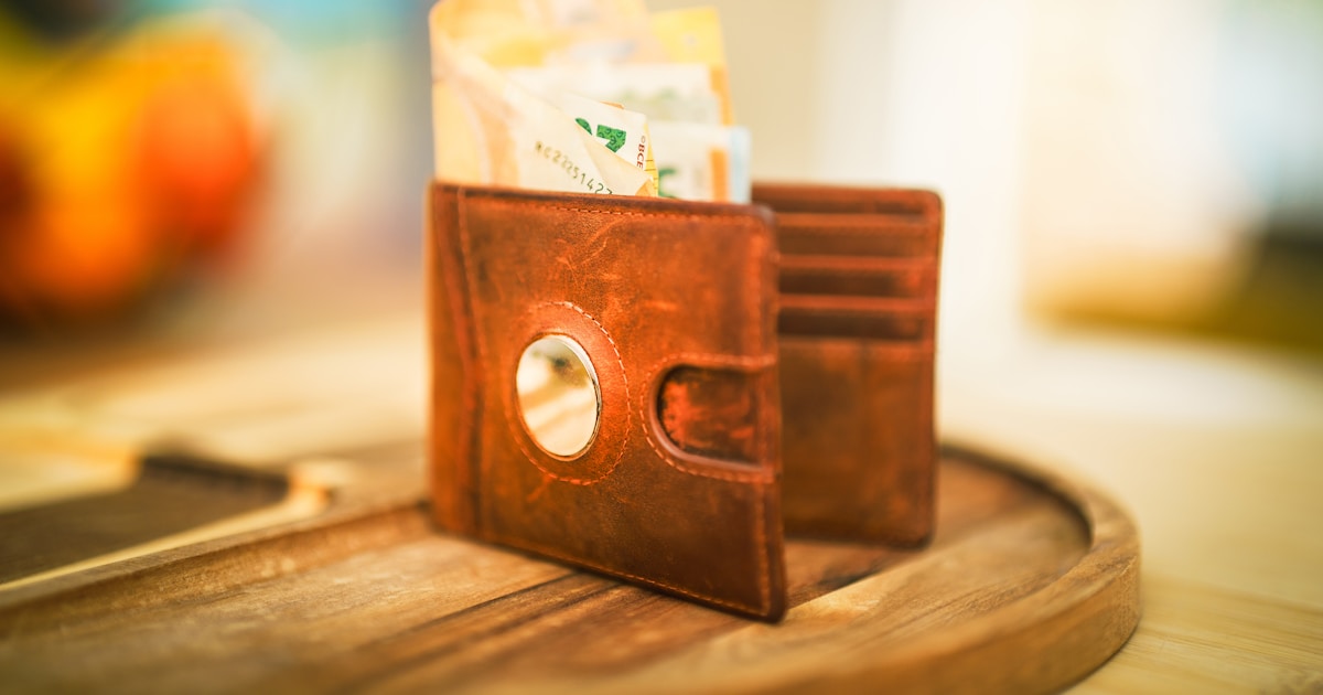An open wallet with cash bills visible, resting on a wooden surface, representing cost management and budget optimization for LLM infrastructure