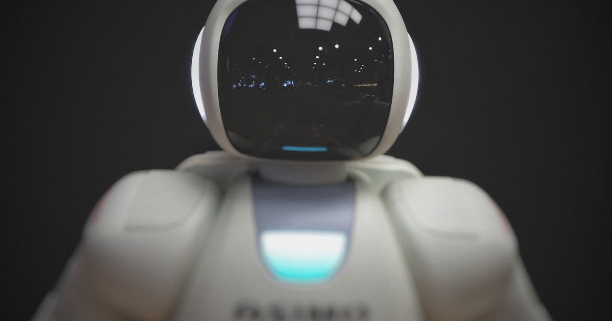 White humanoid robot with dark visor against dark background
